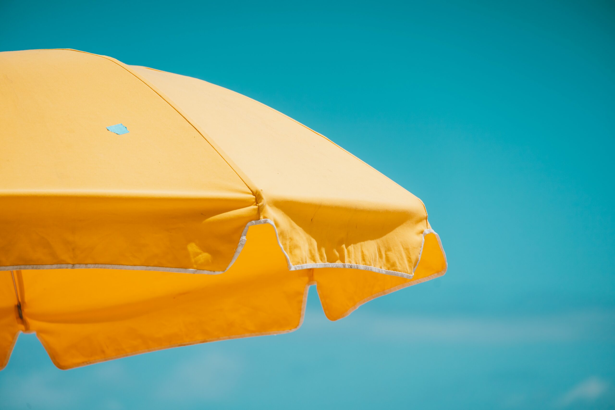pexels-photo-8651447-8651447 A vivid yellow beach umbrella set against a clear blue sky, capturing the essence of summer.